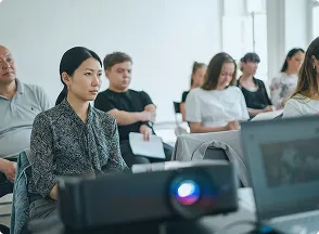 手前にプロジェクターがあり奥に説明を聞いている人が座っている